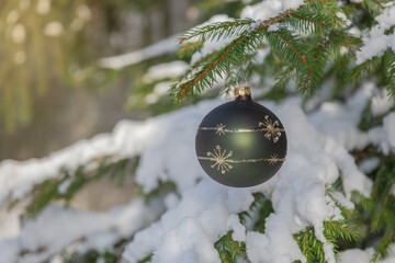 Christmas green bauble hanging on a Christmas tree covered in snow