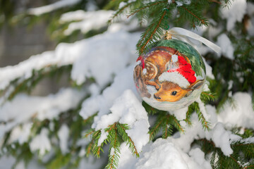 Christmas bauble hanging on a Christmas tree covered in snow