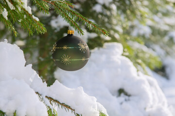 Christmas  green bauble hanging on a Christmas tree covered in snow