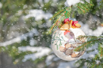 Christmas bauble hanging on a Christmas tree covered in snow