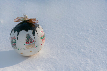 Christmas card. Christmas bauble lying on natural snow on a frosty sunny day.