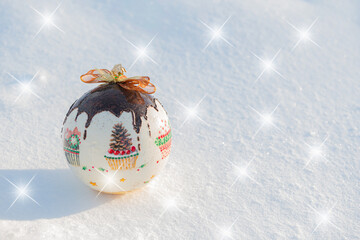 Christmas card. Christmas bauble lying on natural snow on a frosty sunny day, with decorative stars.