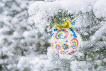 Christmas bauble hanging on a Christmas tree covered in snow
