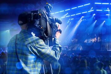 Man operator films concert on camera. Videographer guy back to display. Man director points camera...