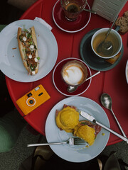 Delicious brunch setup at a café, featuring eggs benedict, coffee, tea, and a colorful table...