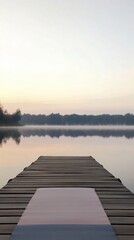 Obraz premium A serene lake view from a wooden dock at dawn, reflecting calm waters and soft colors.