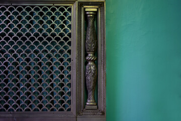 Beautiful forged metal grille covering heating radiators and the wall next to it
