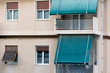 close up on the facade of an apartment building in Athens, Greece with green awnings. 