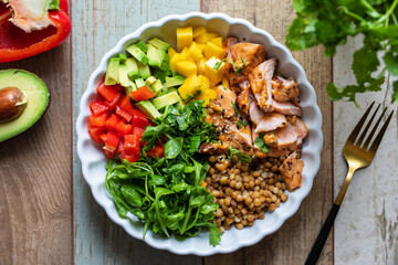 Salad bowl with salmon, lentils, mango, avocado and rocket leaves