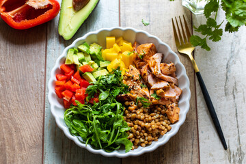 Salad bowl with salmon, lentils, mango, avocado and rocket leaves