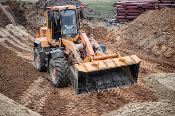 Heavy machinery at work in a construction site leveling earth during a cloudy afternoon, showcasing...