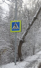 Pedestrian crossing road sign against the background of snow-covered branches, 2