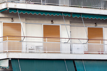 close up on the facade of an apartment building in Athens, Greece with green awnings and brown shutters