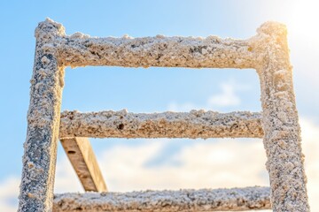 Naklejka premium A weathered ladder covered in salt, set against a bright sky.
