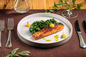 Portion of salmon steak with spinach on restaurant served table