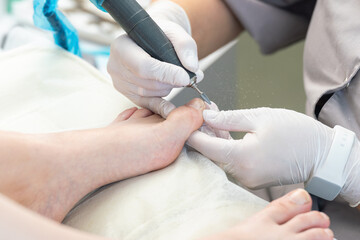 Professional hardware pedicurist, podiatrist cleaning nails using a nail miller