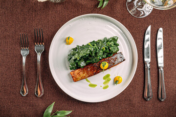 Portion of salmon steak with spinach on restaurant served table