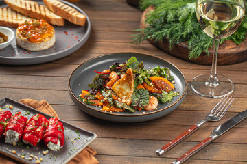 Portion of salad with persimmons and shrimps on wooden served table