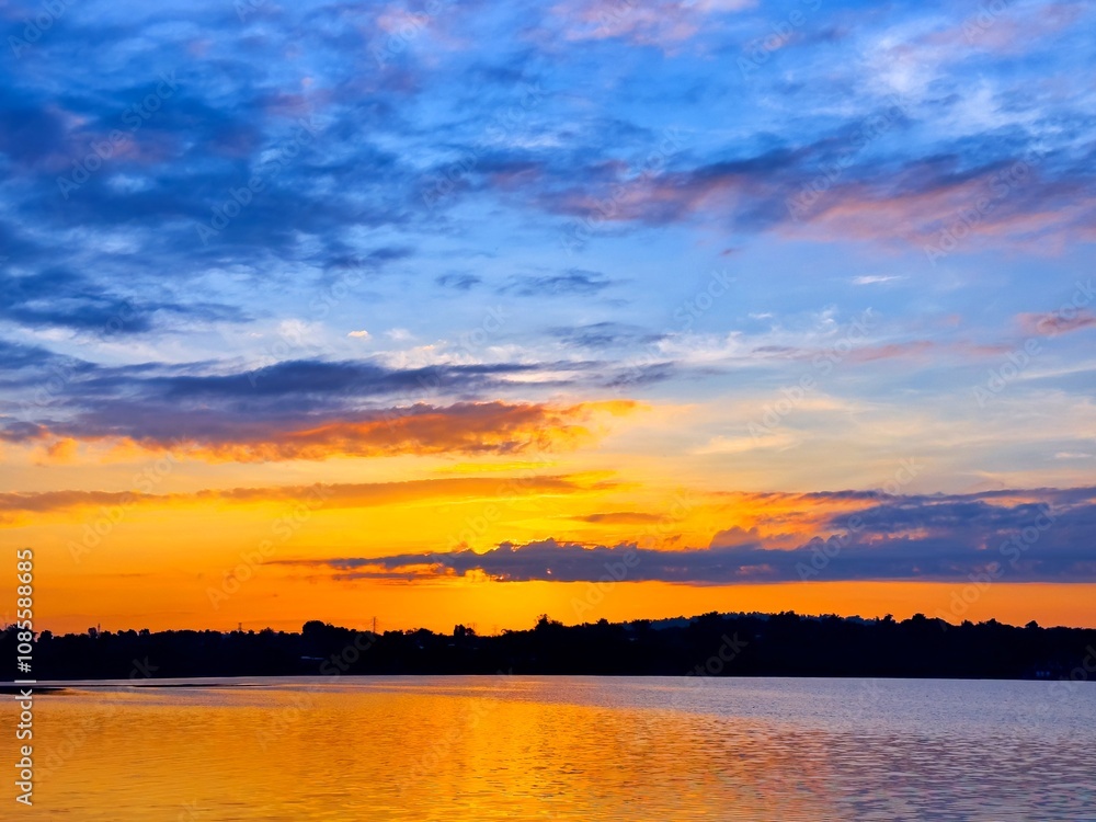 Wall mural vivid colorful color of sunset with clouds.sunset with mountain above lake reflection in water.