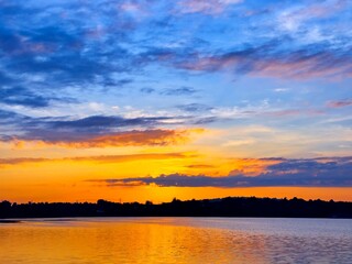 Naklejka premium vivid colorful color of sunset with clouds.Sunset with mountain above lake reflection in water.