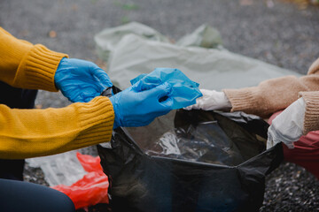 Two Asian women are collecting garbage, working together to clean the environment. They are focused...
