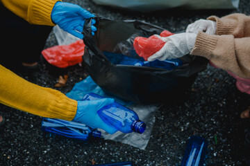 Two Asian women are collecting garbage, working together to clean the environment. They are focused...