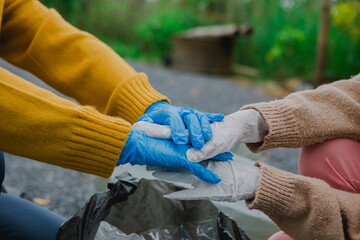 Two Asian women are collecting garbage, working together to clean the environment. They are focused...