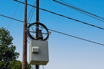 Telecommunications equipment mounted on a utility pole in a suburban area under a clear blue sky...