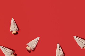 Winter holidays background, snowy white Christmas trees over red paper. 