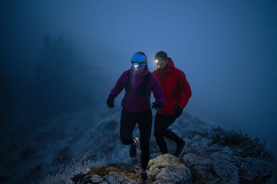 Night trail runner of men and women running on the mountain.at night milky way