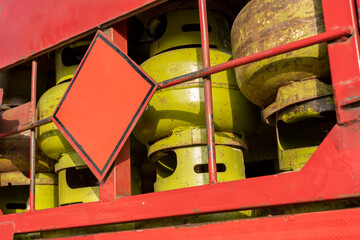A stack of green gas cylinders secured on a red truck with a safety sign. Industrial transportation...