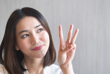 Happy smiling asian woman pointing up three fingers, 3 points gesture