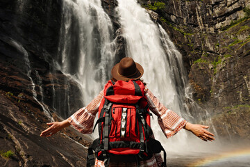 An Adventurous Woman Standing Proudly by a Majestic Waterfall Surrounded by Nature