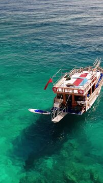 Traditional turkish gulet tourist boat floats on calm turquoise waters beside a rocky coastline, basking in the warm sunlight