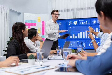 Presentation in office or meeting room with analyst team utilizing BI Fintech to analyze financial data. Businesspeople analyzing BI dashboard power display on TV screen for strategic planning.Prudent