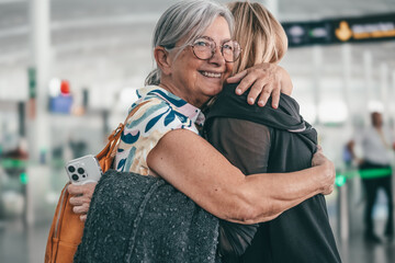 Couple of women hugging and goodbye in airport area for arriving or departing trip, feeling for long distance relationship. Two mature women embracing each other affectionately before leaving