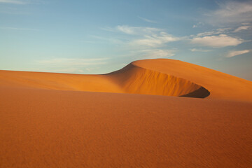 Curved sand dunes at sunset