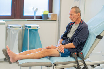 middle aged man sits deep in thought on a medical couch in a clinic office, waiting for the doctor...