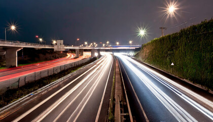 A vibrant red and white highway stretches through lush green hills under a dramatic sky at sunset