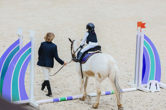 Show jumping competitions for children on ponies. Pony class with handler. Cavaletti with handler. Aerial views