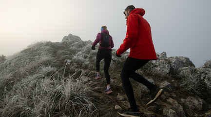 trail running couple man and woman running on a mountain path