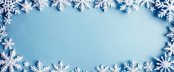 Snowflakes of different sizes and shapes creating a winter frame on a light blue background with a brighter central area. Christmas template.