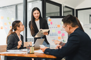 business meeting with professionals discussing data and strategies. woman presents information using tablet, while colleagues engage with charts and notes