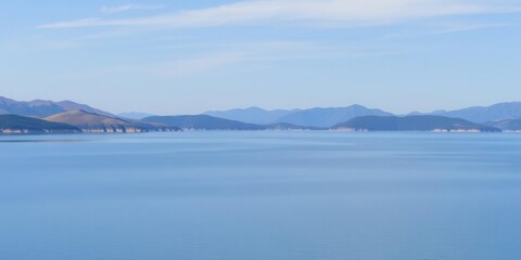 A panoramic view of rolling hills and a serene lake under a clear blue sky, panoramic, water, tranquil