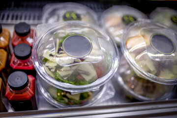 Fresh made salad packed in plastic container in the store next to natural healthy juices.