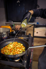 Chef frying cut vegetables in pan in restaurant kitchen.