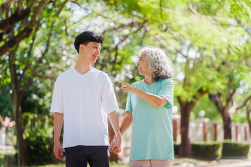 Young son and his mature mom asian people share loving hug in beautiful park, surrounded by nature. Their happiness radiates as they bond outdoors, celebrating family love and togetherness.