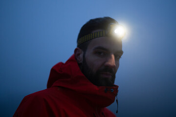 Hiker or triathlon trail runner with a headlamp on a trail in the mountain with fog at night © .shock