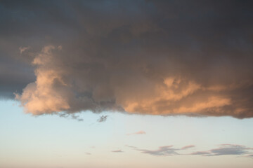 Dramatic storm clouds gather in the sky, partially lit by the warm hues of the setting sun. 