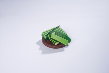 Sticky layer cake or Kue Lapis on wooden plate isolated on white background. Indonesian traditional...